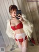 A woman in a red bra and white lingerie taking a selfie.
