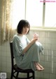 A woman sitting on a chair holding a glass of water.