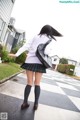 A woman in a school uniform is walking down the street.