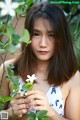 A young woman holding a white flower in her hands.